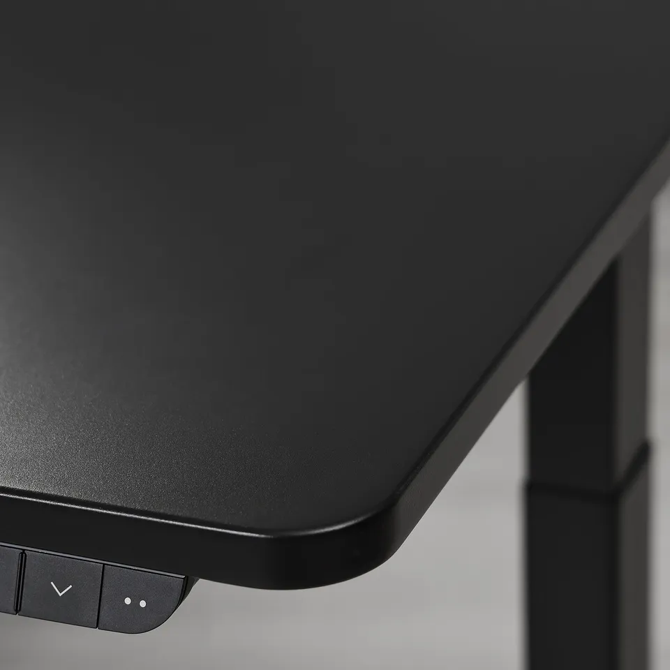Close-up of a sleek, black, high-quality adjustable gaming desk with minimalist controls.
