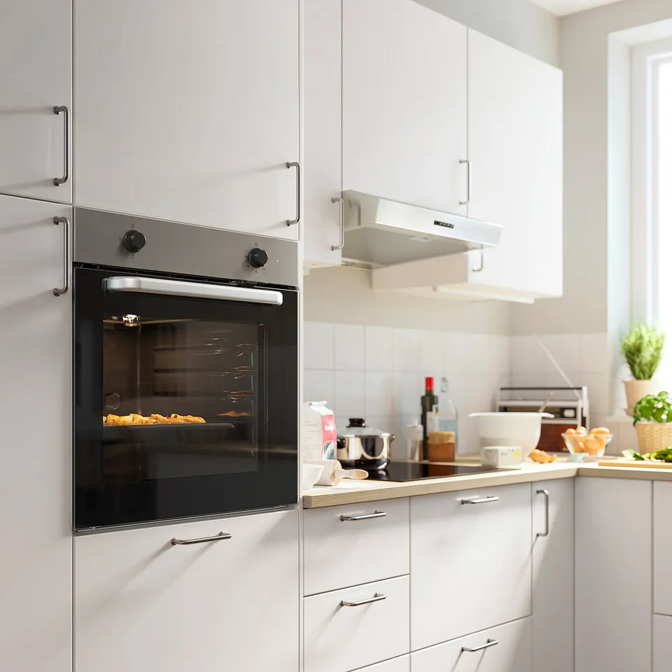 Modern kitchen with LAGAN stainless steel built-in oven, surrounded by white cabinets and countertops with kitchen items.