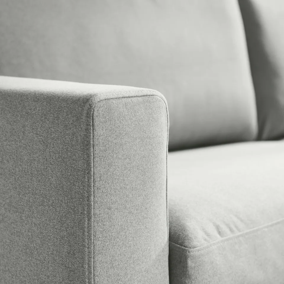 Close-up of a modern, upholstered armchair corner showcasing smooth, high-quality fabric and neat stitching.