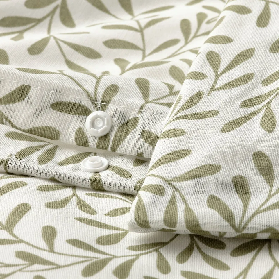 Close-up of a leaf-patterned duvet cover with press-stud fasteners. Shows crease-free, breathable fabric blend.