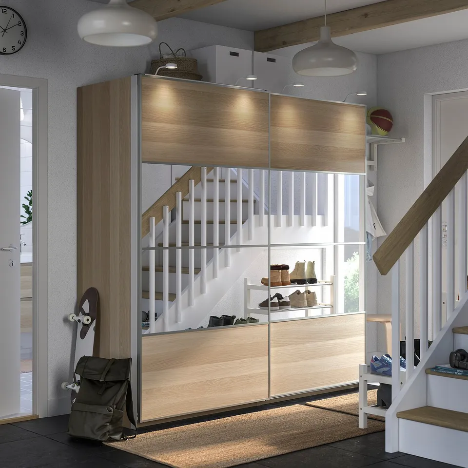A modern entryway with light wood PAX storage, white stairs, and hanging lights.