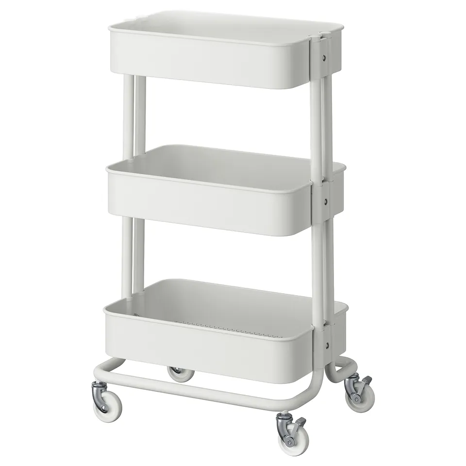 A white, metal, two-tier, rolling utility cart labelled RÅSKOG. It has a rectangular shape and four lockable wheels for stability and mobility.