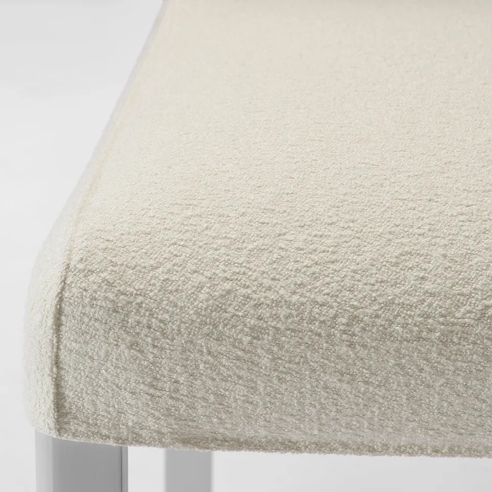 A close-up of a beige upholstered chair with a textured fabric, emphasising its soft and durable quality.