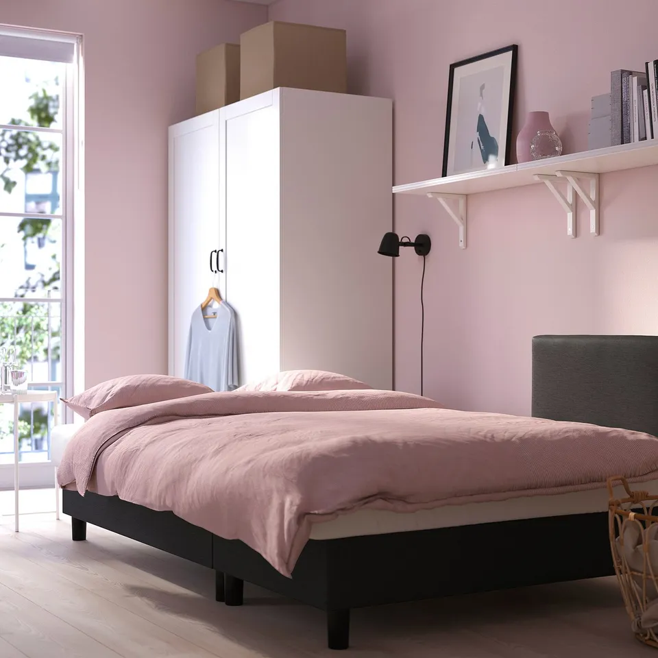 A modern bedroom featuring a pink-themed decor with a bed, wardrobe, and shelves; essentials for comfort and organisation.