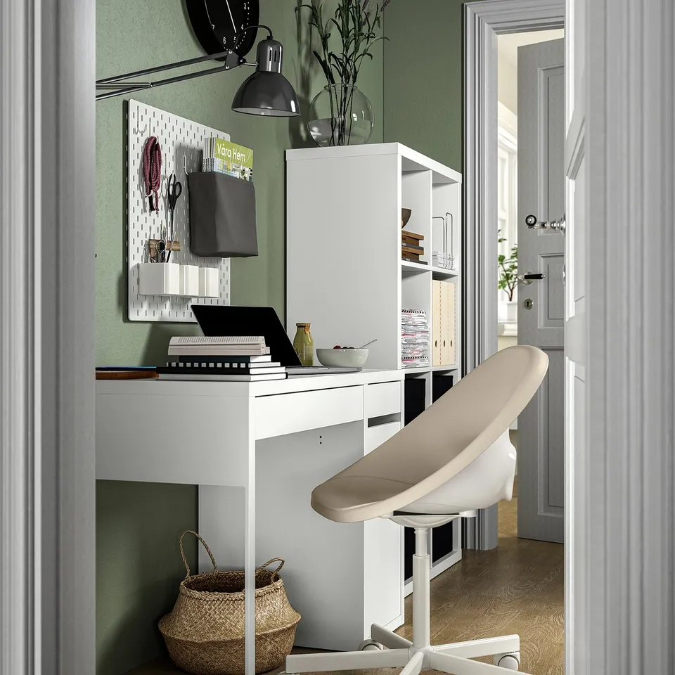 Home office with white ELDBERGET chair, desk, pegboard, and green walls. Simplistic, ergonomic design.