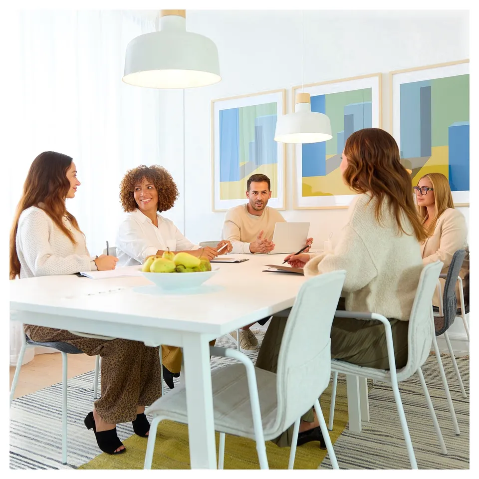 Group at white MITTZON conference table in modern meeting room with abstract art.