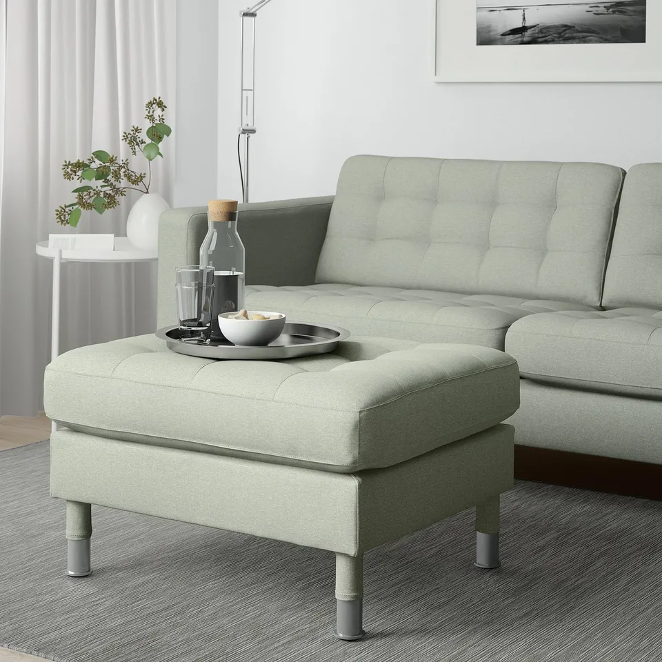 Green LANDSKRONA footstool with wooden legs, living room, beside matching sofa, tray with drink & snacks.