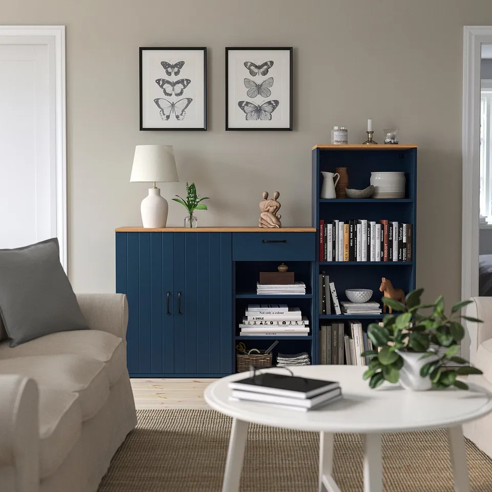 Cosy living room with blue storage, butterfly prints, beige sofa, white table, and decorated bookshelf.