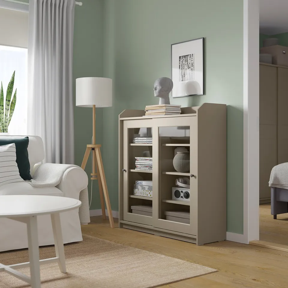 Modern living room with green walls, HAUGA cabinet, white sofa, coffee table, lamp, and plant.