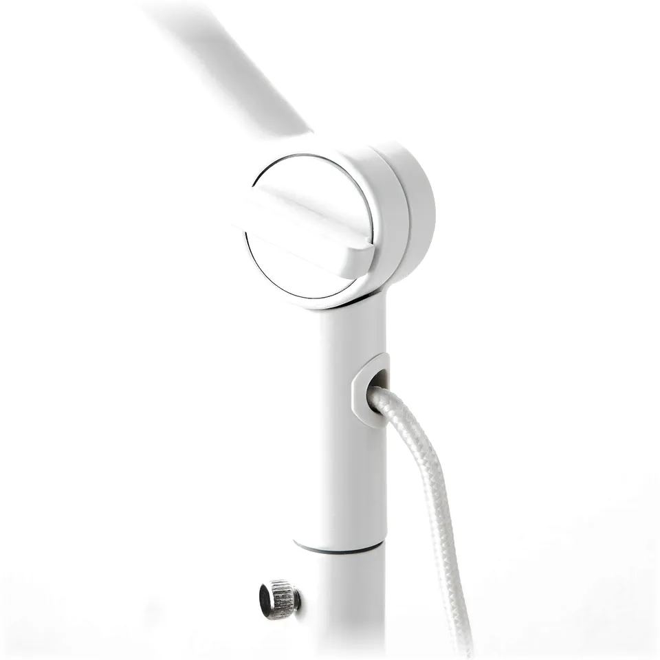 Close-up of modern, adjustable floor lamp in white, focusing on metal joints and cord.