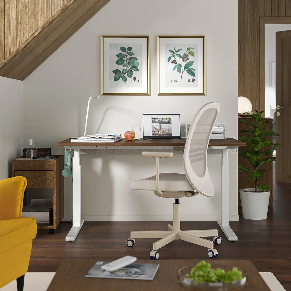 Modern home office setup with a white ergonomic chair, wooden desk, laptop, and decorations.