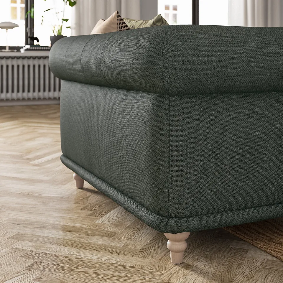 Dark green VISKAFORS armchair with rounded shape, wooden legs, on wooden floor.