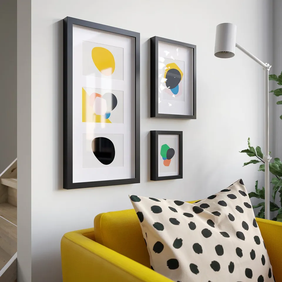 Modern living space featuring yellow, black, and white framed art above a bright yellow couch with leopard-print pillows.