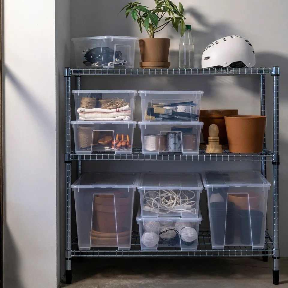 SAMLA storage boxes in clear plastic, various sizes. Shelves hold helmets, plant pots, accessories. Wire shelf unit.