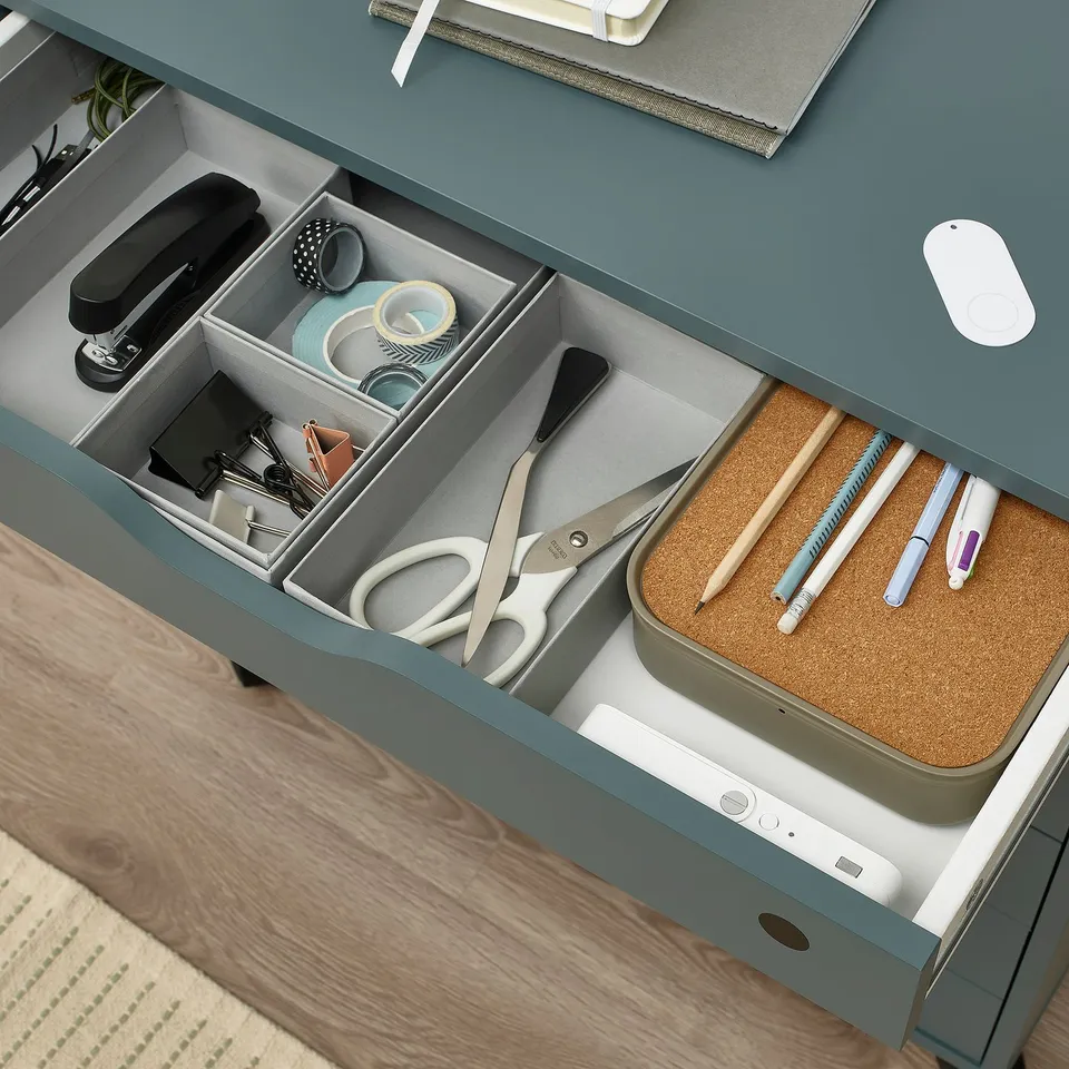 Open desk drawer with organised office supplies including scissors, pencils, and tape, demonstrating SOLSTOLs secure storage function.