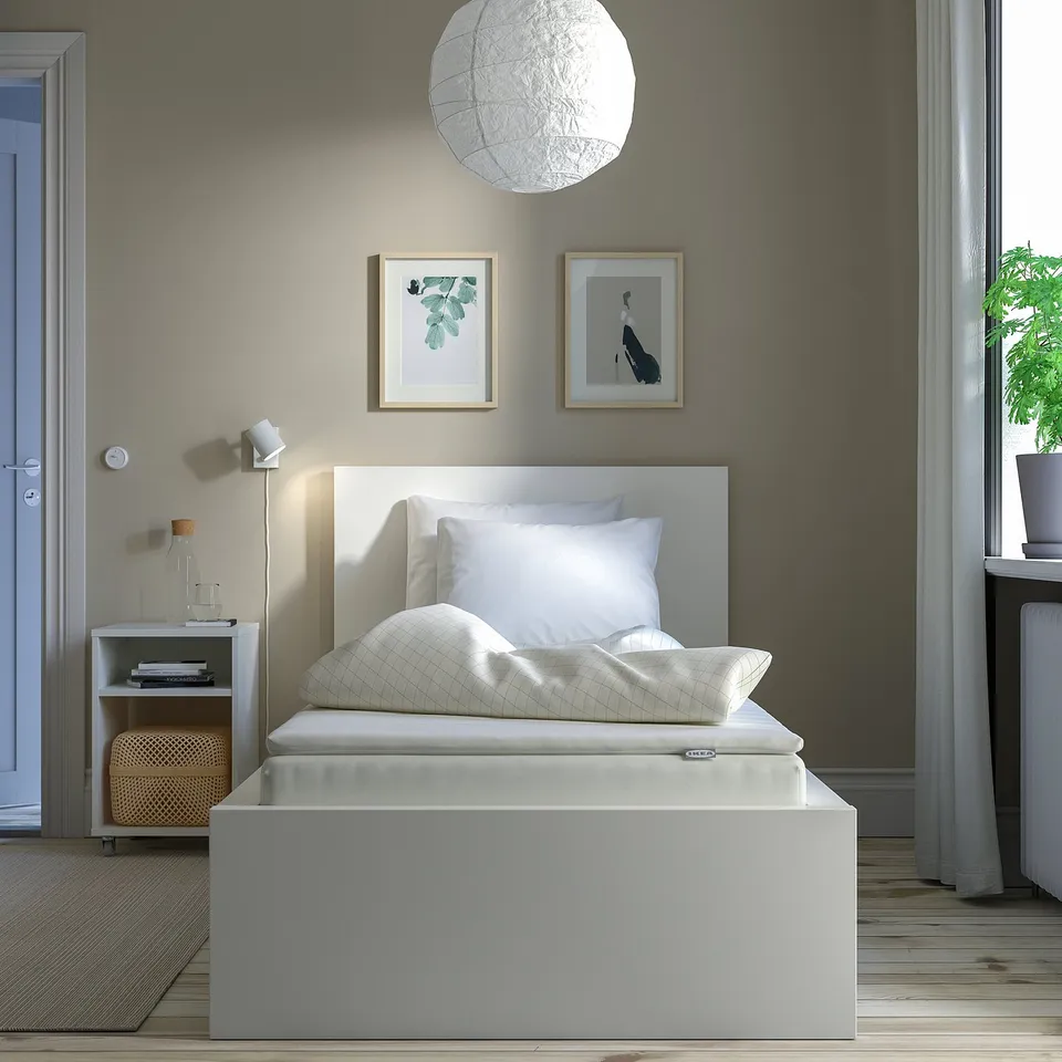 Minimalist bedroom with white NÄSFJÄLLET bed, sheer curtains, and pendant light.