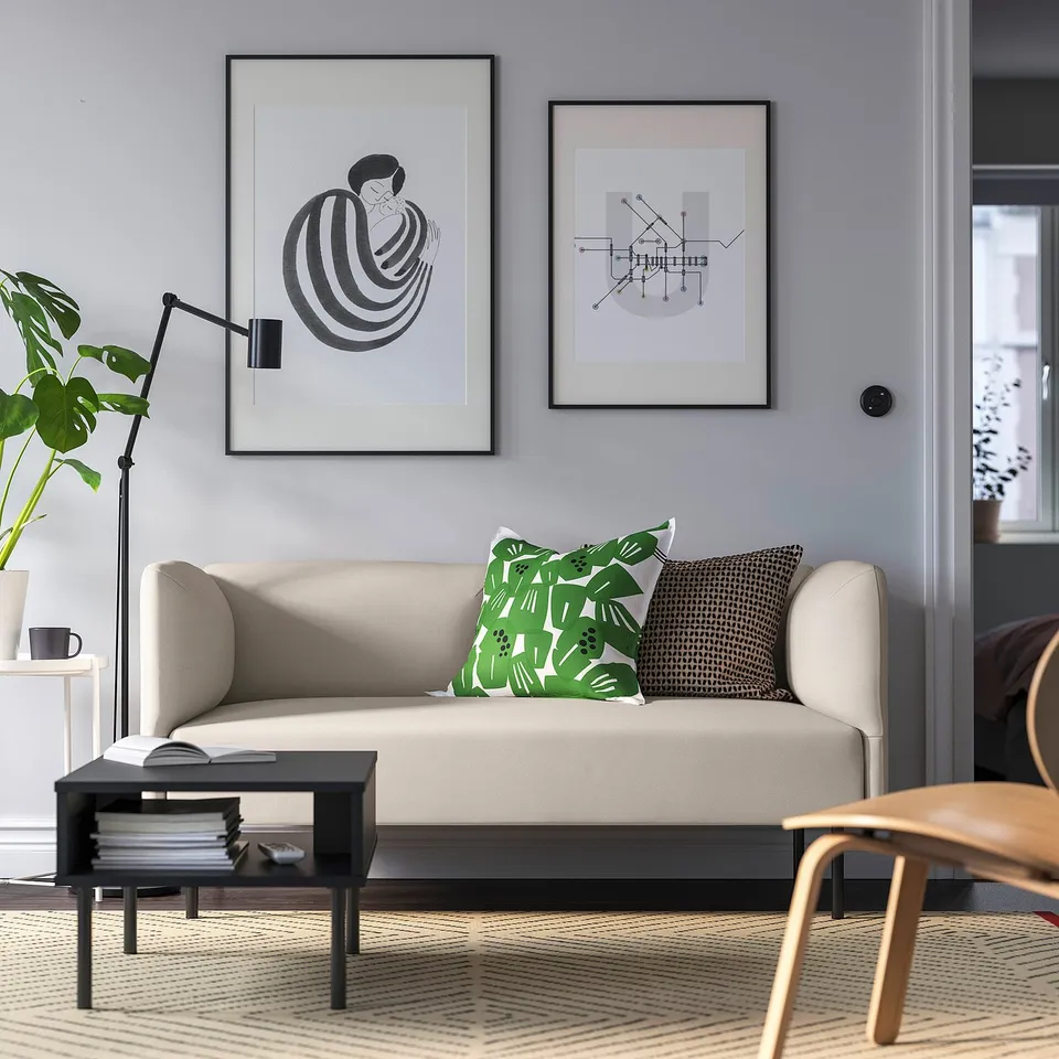Modern living room with beige modular sofa, green cushions, art, lamp, and plant.