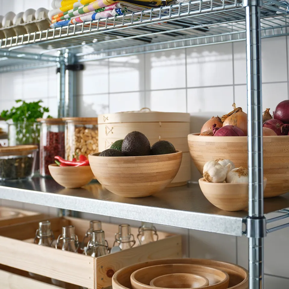 Metal shelving unit with wooden bowls and jars; avocados and onions in bowls, spices in jars.