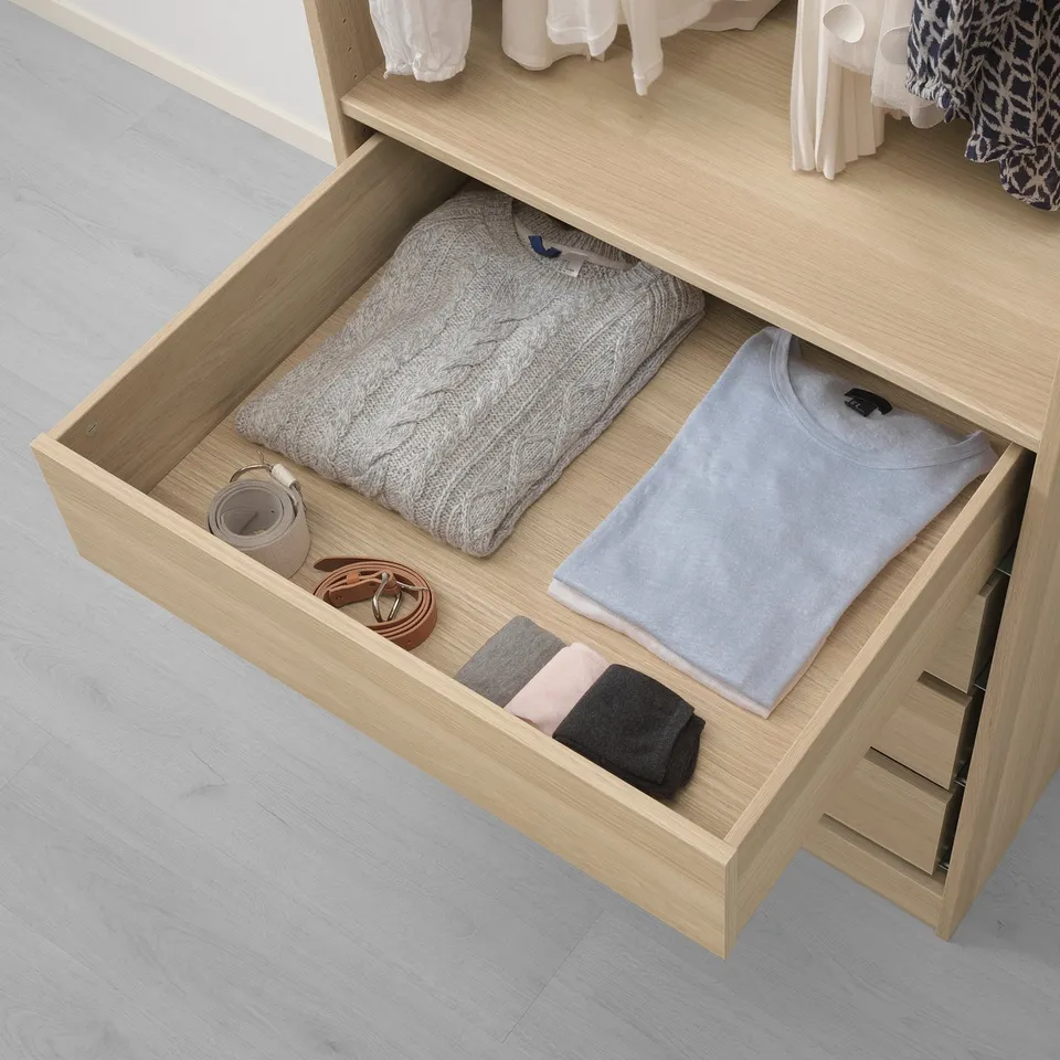 KOMPLEMENT drawer shows neatly folded clothes and accessories, with space for more items in separate compartments.