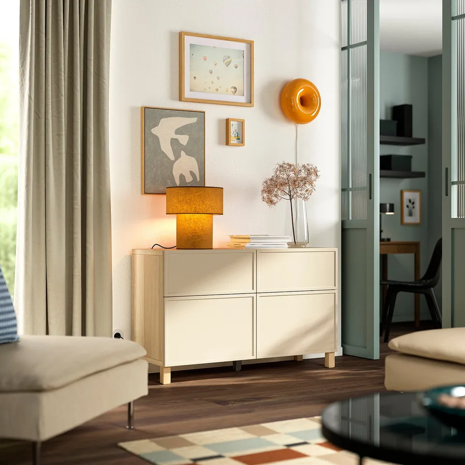 White BESTÅ sideboard with 4 drawers and shelves in a cosy room with decor.