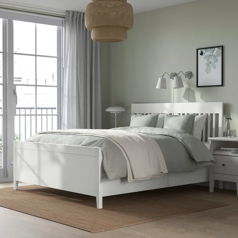 Modern bedroom with IDANÄS bed, storage, green walls, large window, lamp, bedside table, art.