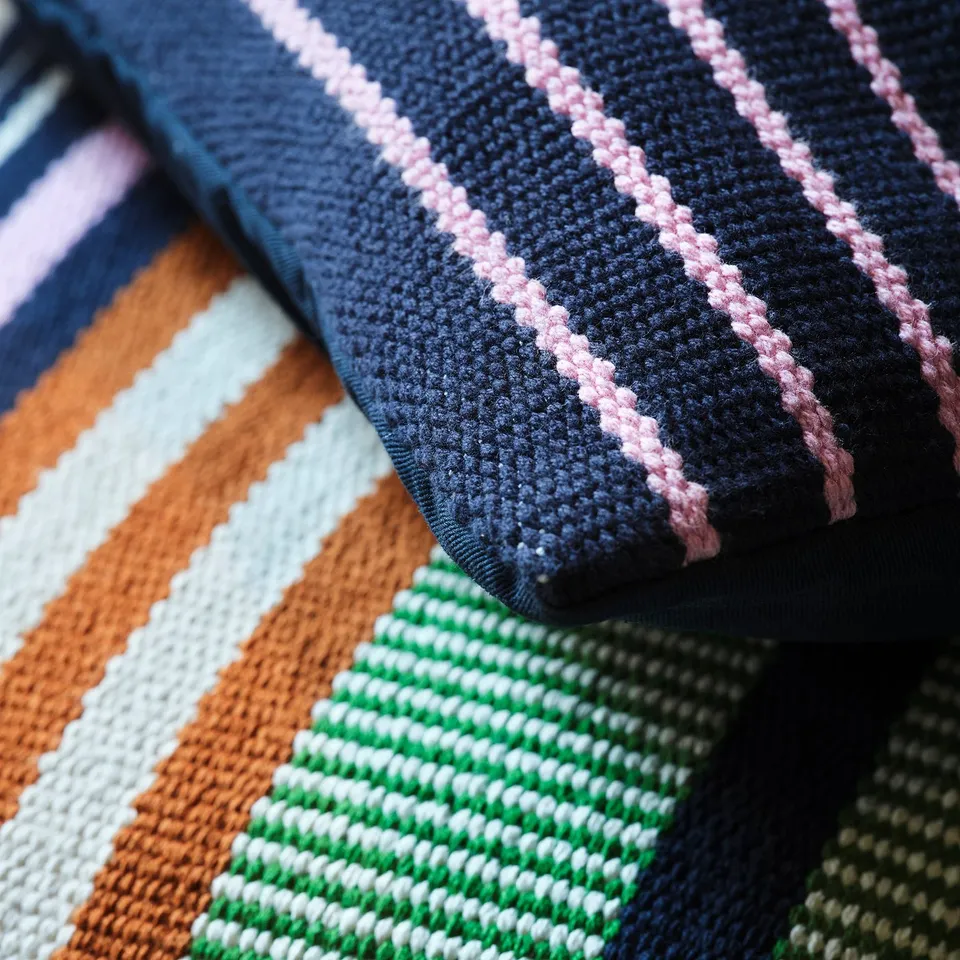 Handwoven cushion covers in vibrant stripes, showcasing intricate craftsmanship and textured cotton.