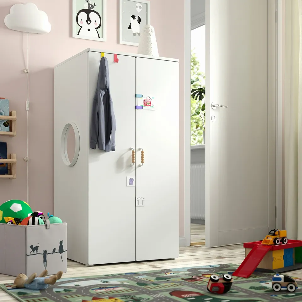Childs room with SMÅSTAD cabinet, mirror doors, blue jacket, stickers, toy box, pink walls, large window.