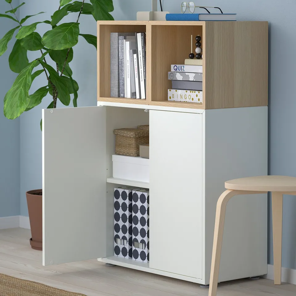 White and light wood storage unit with open and closed shelves, displaying books and boxes.