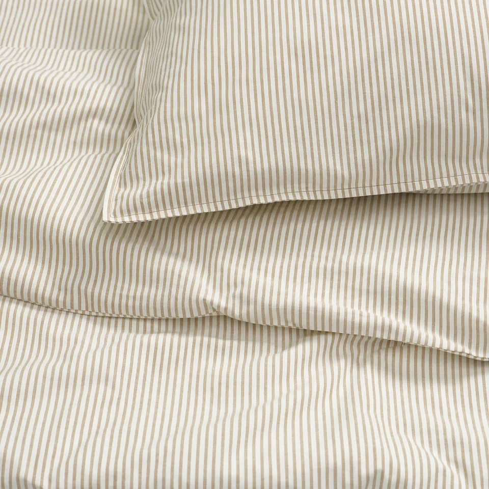 Striped bedding with beige and white lines, neatly folded, showcasing soft, high-quality cotton texture.