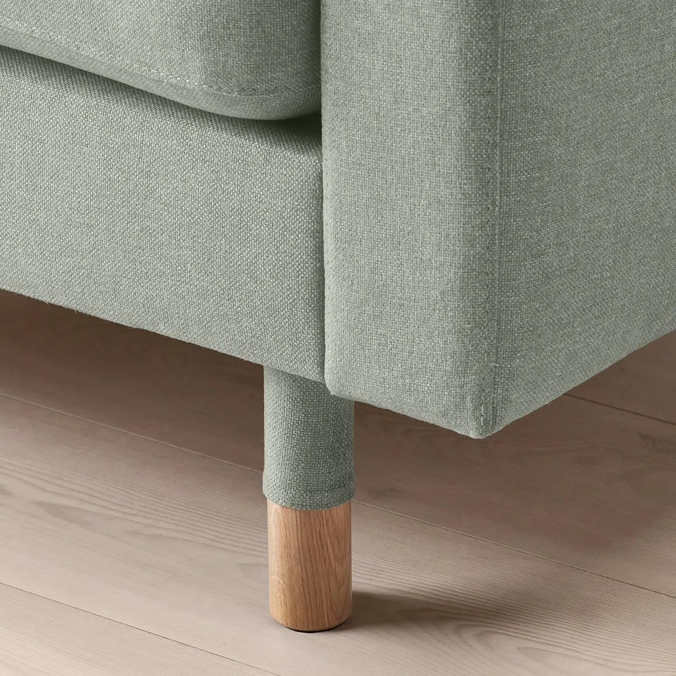 Modern grey sofa with cushions, stylish oak legs, high-quality upholstery, cosy design.