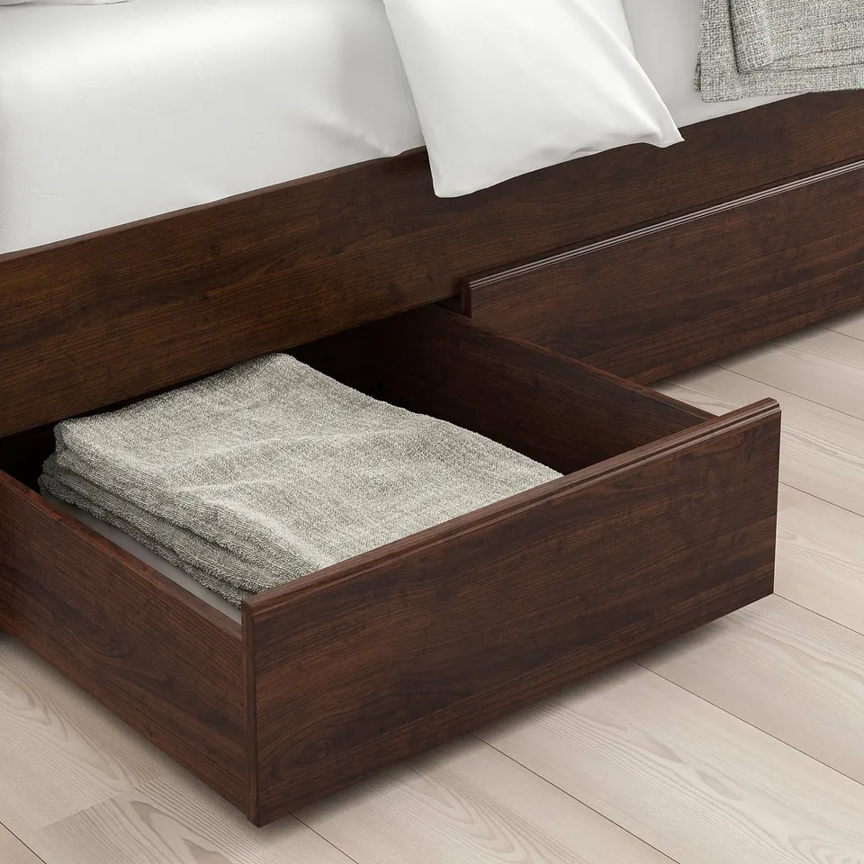 Bed with open drawer showing folded linens, dark wood frame.