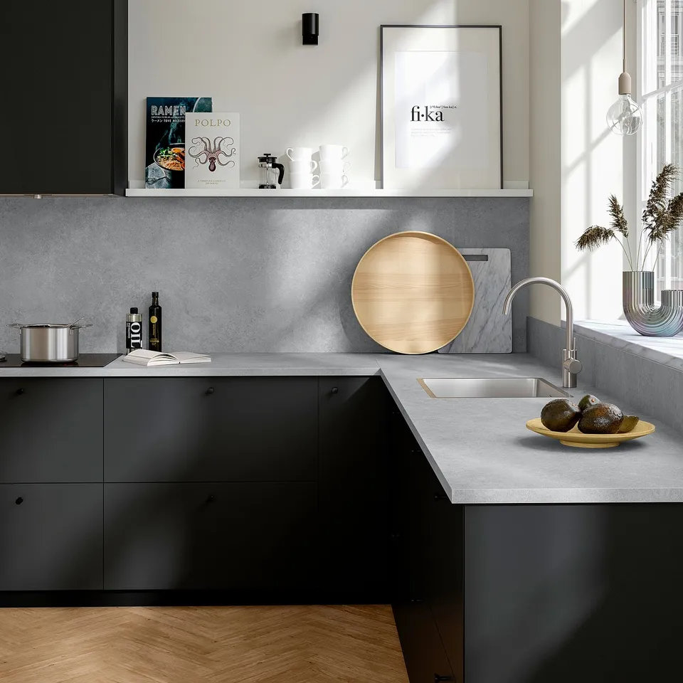Modern kitchen with EKBACKEN grey countertop, sleek design, housing cookware, veggies, and decor, featuring a large circular wooden board.