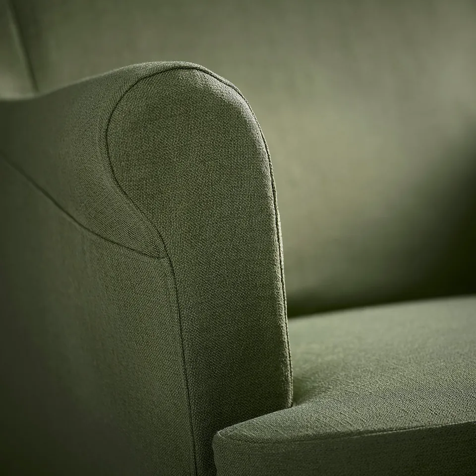 Close-up of a modern, olive green fabric armchair, showcasing its sleek design and high-quality texture.