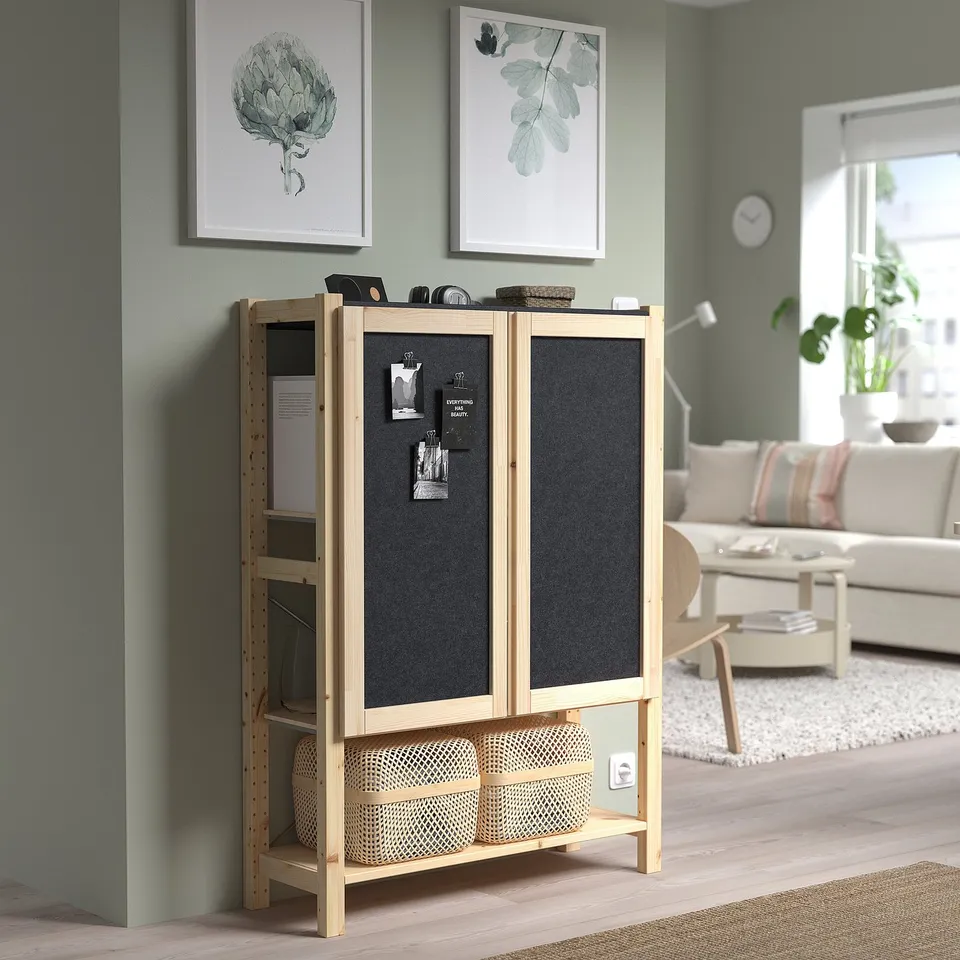 IVAR storage unit with black doors in green room, housing items, contrasting with painting and couch.