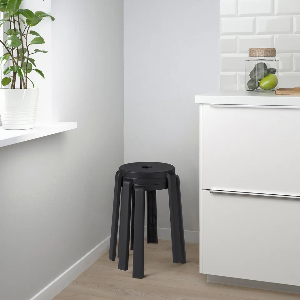 Black stackable stool beside white cabinets in kitchen.