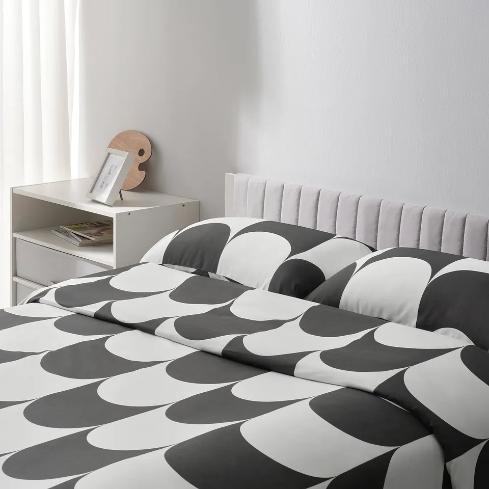 Bed with striped quilt, white headboard, storage shelf with books, and circular wooden decoration.