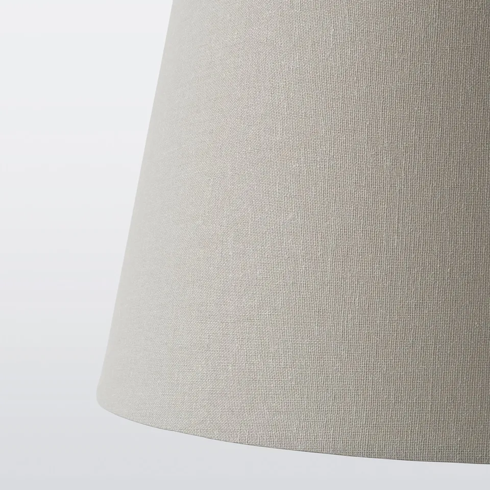 Close-up of SKOTTORP lamp shade, soft off-white fabric texture, diffusing gentle light.