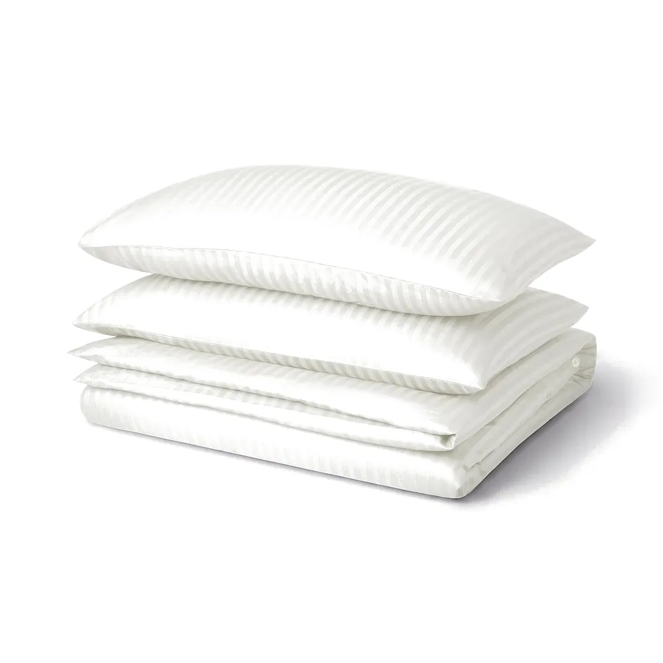 Three white pillows and a folded duvet, NATTJASMIN cotton blend with subtle stripes.