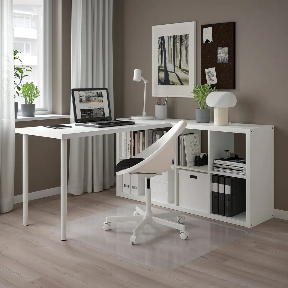 Modern home office with white KALLAX shelving, desk, and chair. Plants, lamp, and organised books. Clean, minimalist design.
