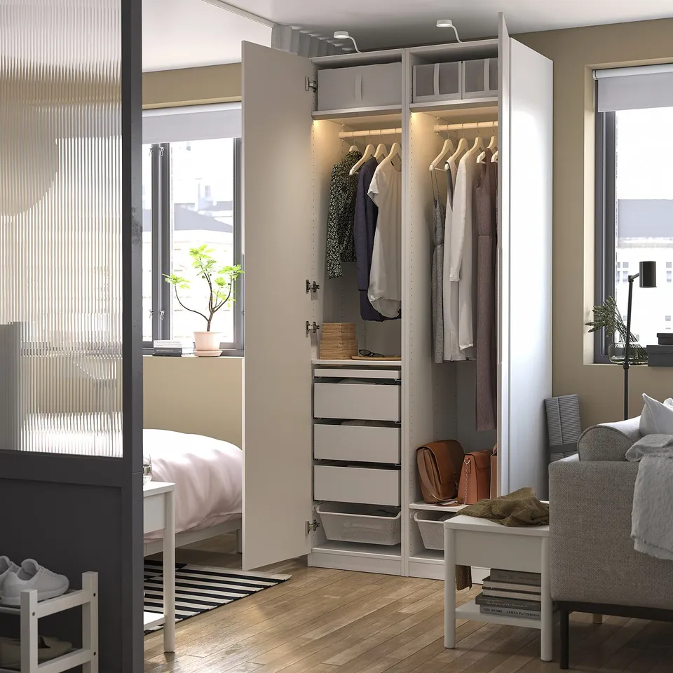 Modern bedroom with open wardrobe displaying clothes, drawers, and integrated lighting.