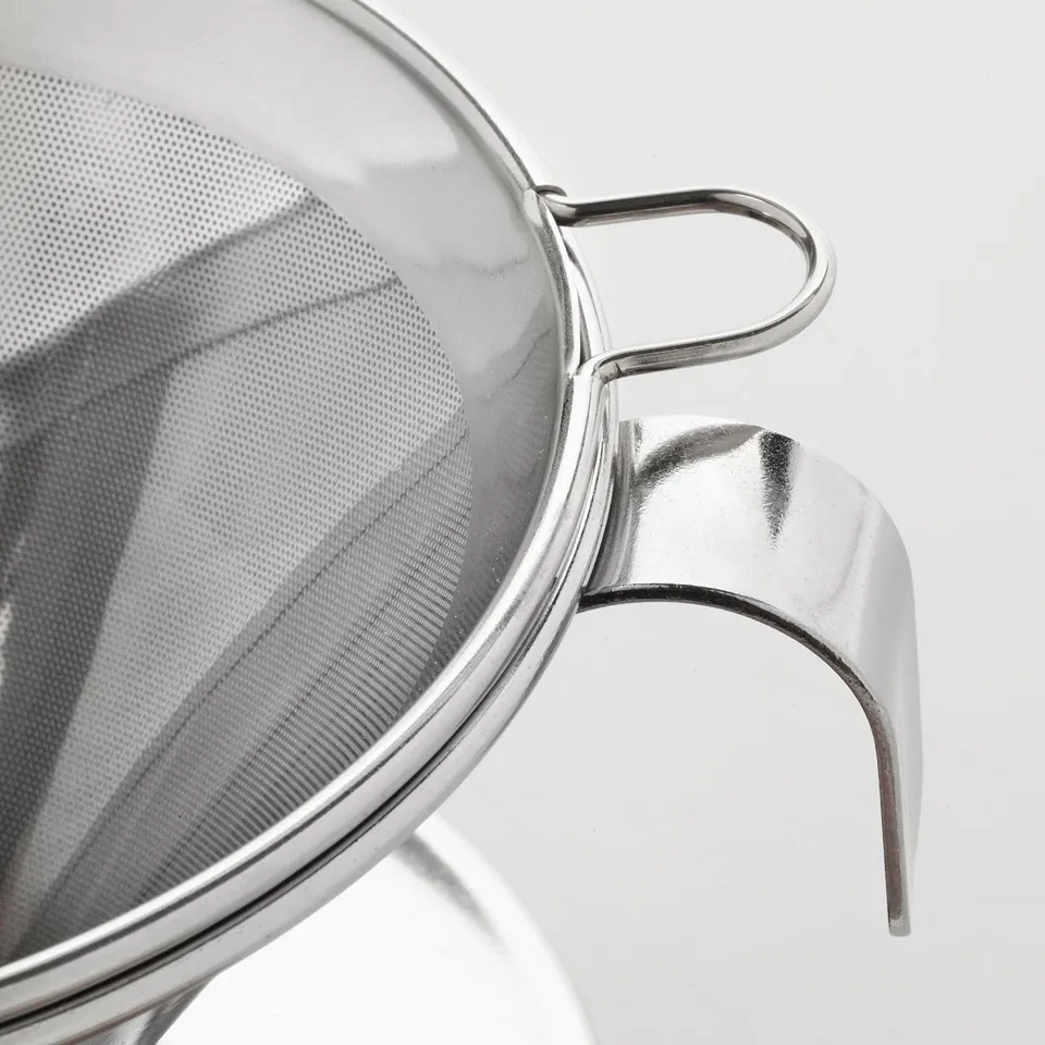 Stainless steel coffee philtre with secure handles reflects light, emphasising its polished, durable surface.