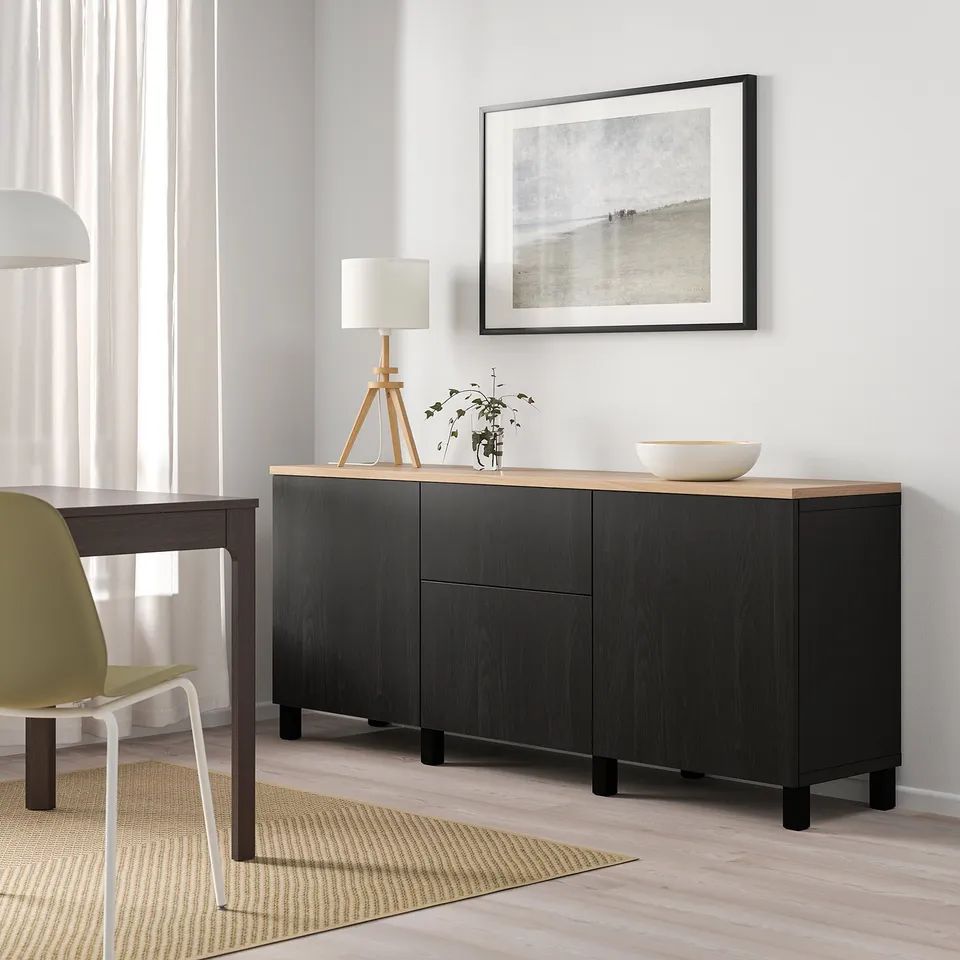 Minimalist living room with black BESTÅ sideboard, yellow chair, simple lamp, and art.