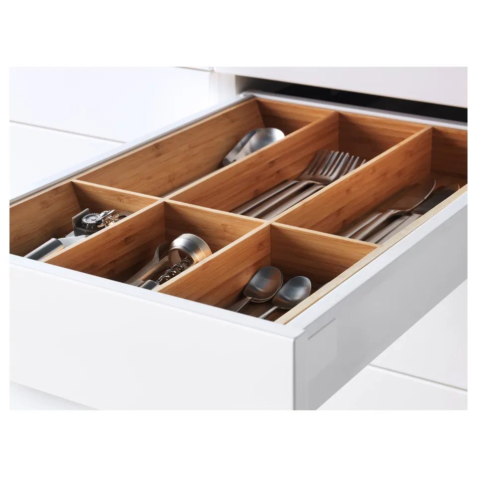 Open kitchen drawer with wooden dividers, storing various utensils and cutlery.