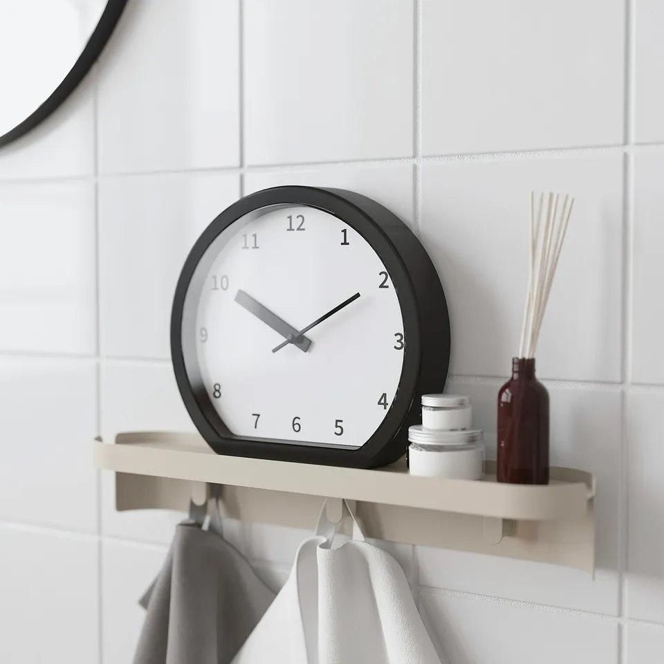 Clock on shelf with towels, showing time.