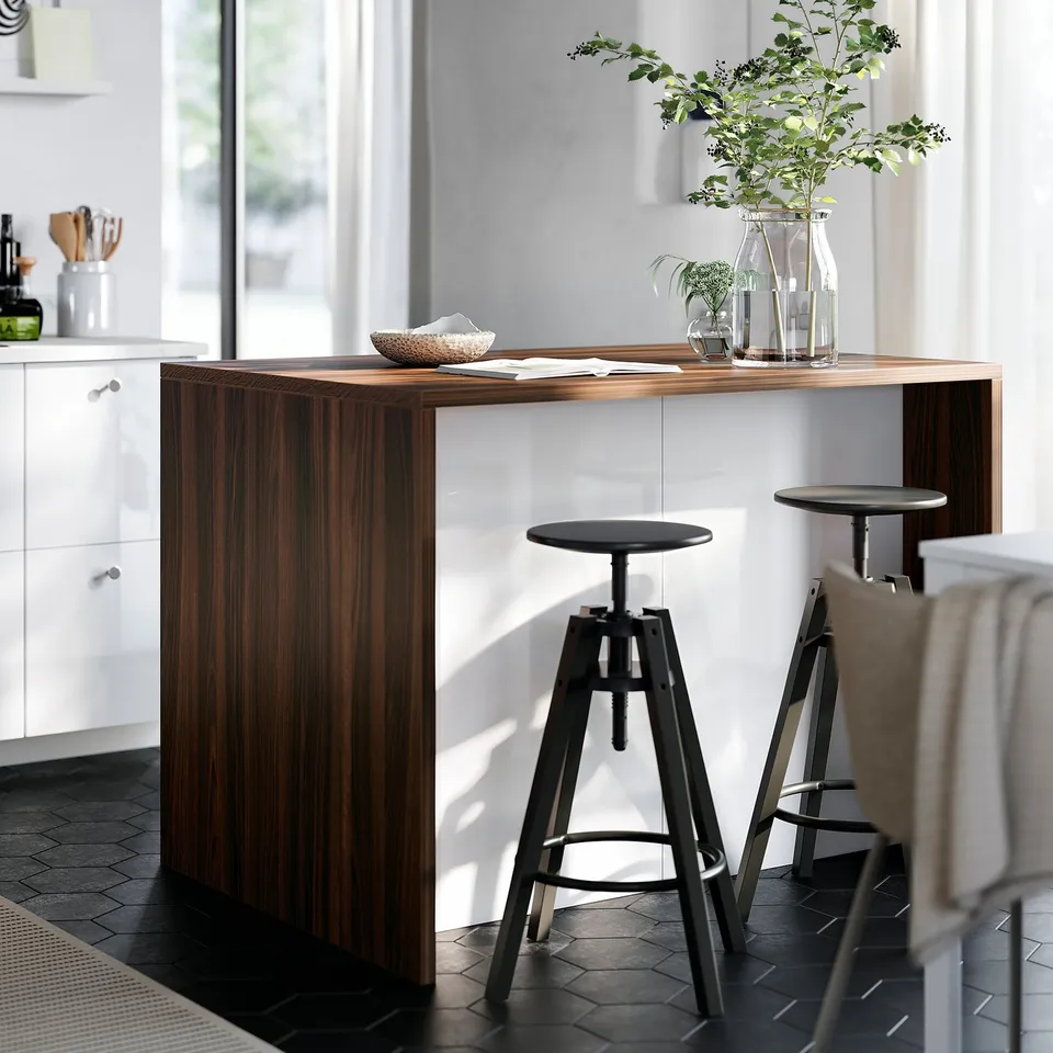 Modern kitchen with DALFRED bar table, stools, white cabinets, and vases with greenery.