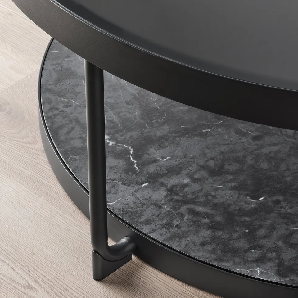 Modern round side table with smoked glass top and black metal legs, showcasing a sleek and sturdy design.