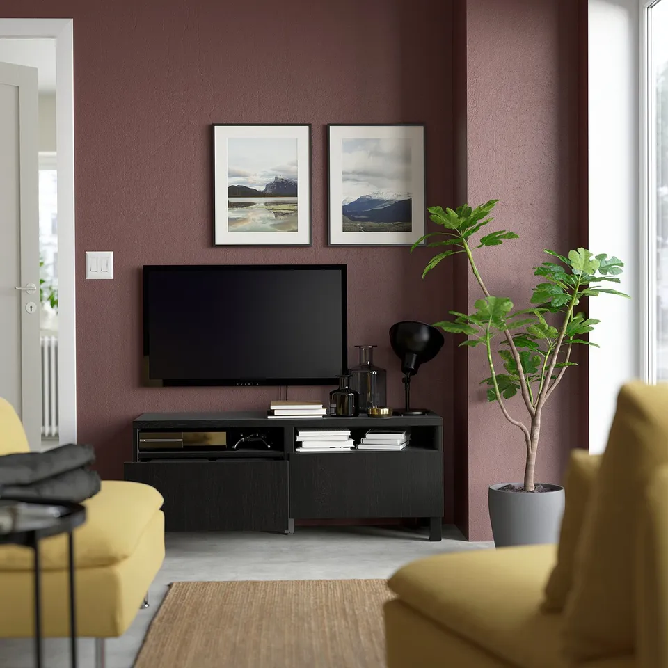 Modern living room with black BESTÅ tv stand, yellow couches, and potted plant