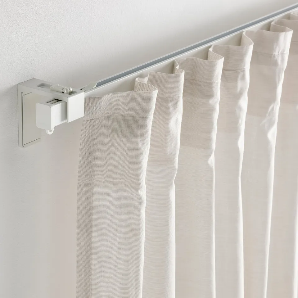 White curtains hang from modern ceiling track, held by white bracket.