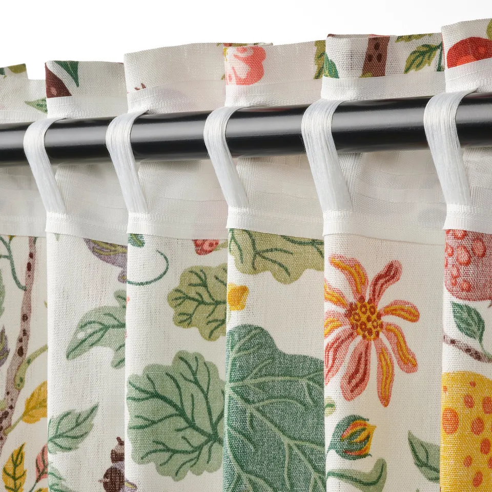 Floral curtains with looped rod pockets hang pleated, crafted from cotton and ramie, filtering light, offering privacy.
