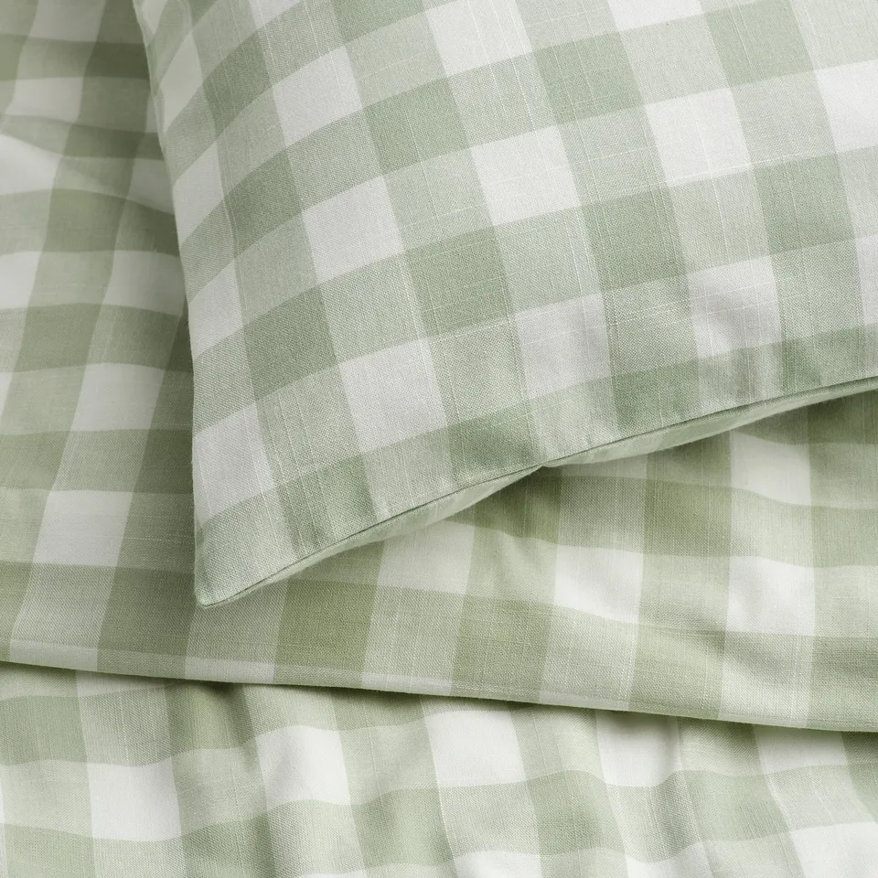 Gingham duvet cover, pale green and white, neatly folded, showcasing quality fabric texture. 100% organic cotton, soft to touch.